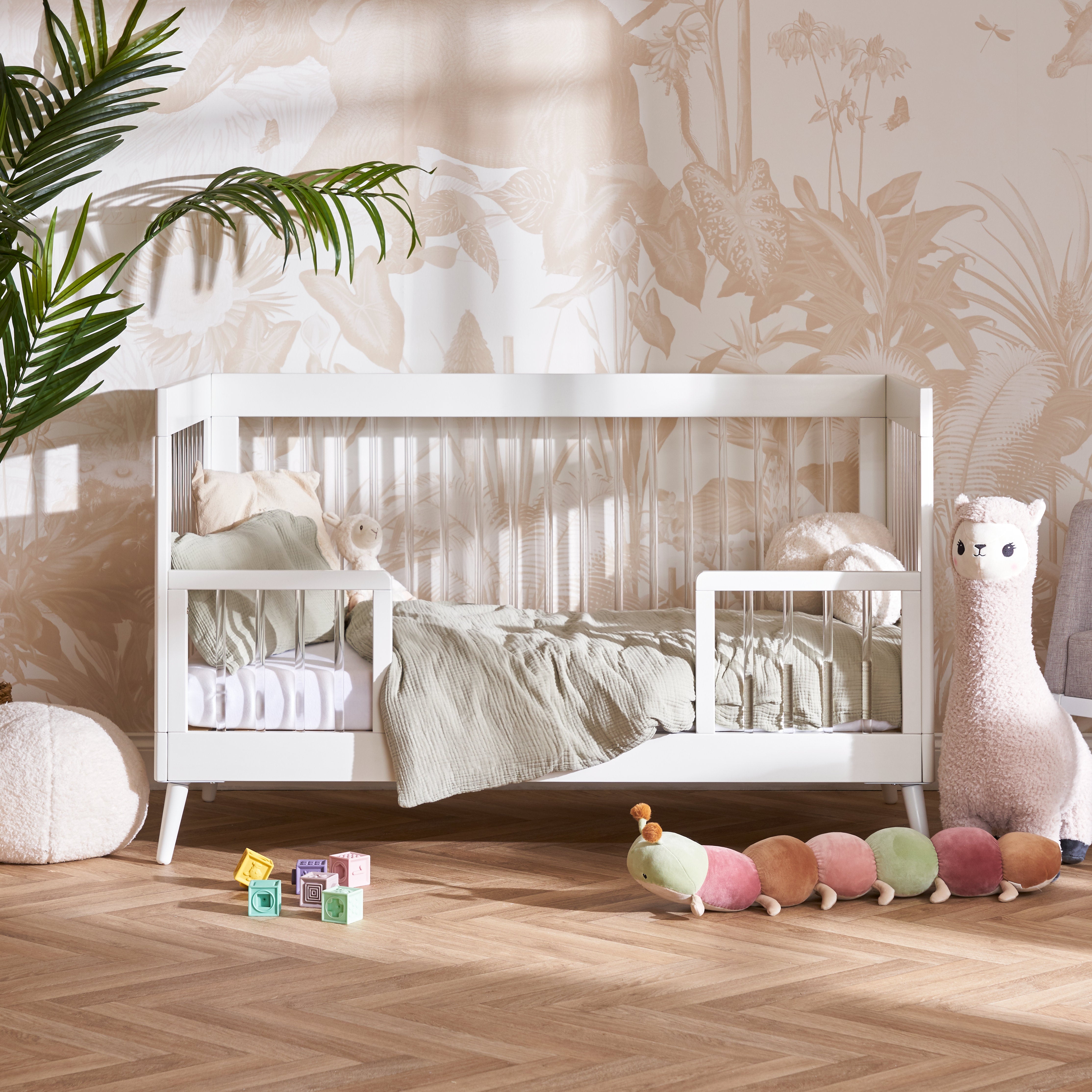 Acrylic Cot Bed with toddler safety rails fitted on the front.