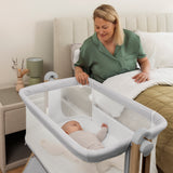 Mum in her own bed with baby in own crib with mesh sides. Window zipped up.