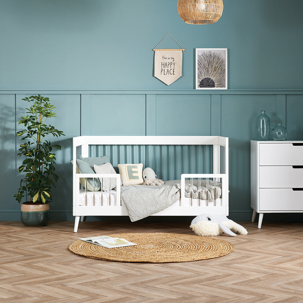Scandi style acrylic cot bed with toddler safety rail attached.