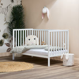 White cot bed, in day bed mode with rails on all 3 sides, low mattress setting for toddlers easy access.