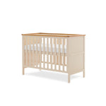 Mini Cot bed, solid end with trim on top, base on the new born setting.