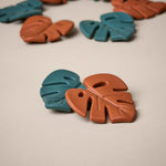 2 leaf shaped teethers, 1 in dark green colour and 1 in a burnt orange colour
