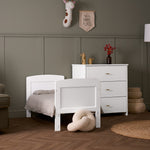 White Mini Cot Bed converted into a toddler bed, with matching  3 drawer dresser, with gold T bar handles. 