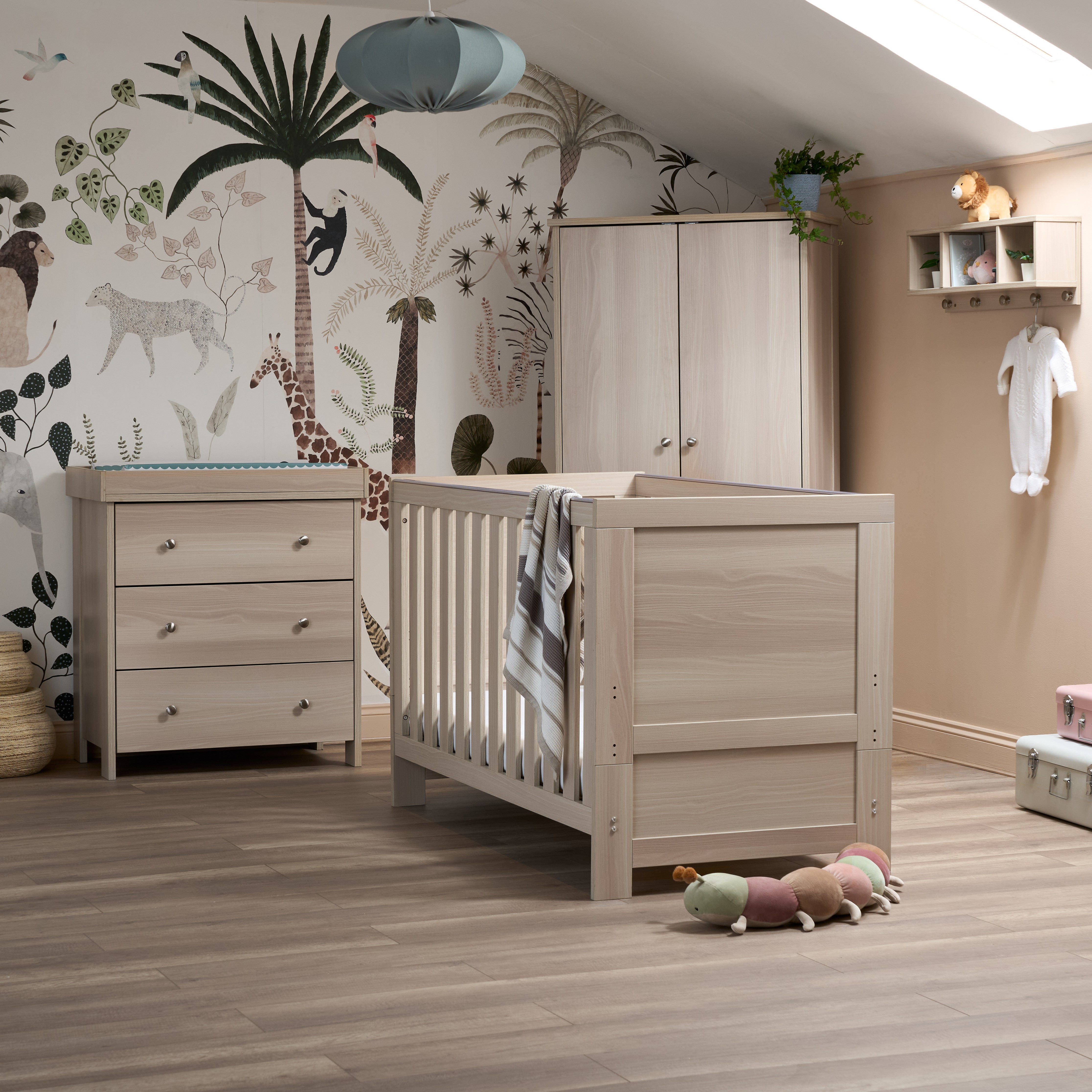 Nursery room with wooden crib, dresser, and decorative wall mural.