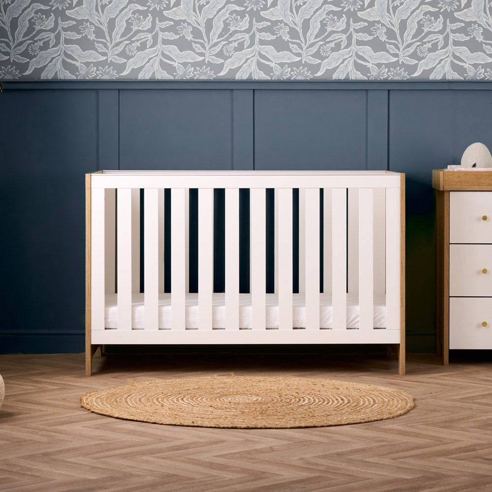 Contemporary cot bed with oak ends & thick white rails with teething rails. Based fitted on the lowest setting. 