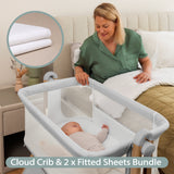 Grey Bedside crib with wood effect frame. mesh sides, with sleeping baby in crib & mum looking on from her own bed & mini shot of muslin fitted sheet.