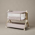 Bedside crib with taupe woven fabric, mesh sides, zipped up parent window, wood effect frame with ivory plastics & wheels. Storage basket underneath. 