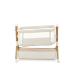 Bedside crib, in oatmeal with wood effect frame, crib positioned on a tilt to help with colic, storage basket underneath the crib.
