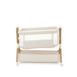 Bedside crib, in oatmeal with wood effect frame, crib positioned on a tilt to help with colic, storage basket underneath the crib.