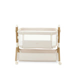 bedside crib on middle setting, oatmeal fabric with mesh sides, parent side has zipped panel that can be opened for easy access to the baby. wood effect frame & storage basket underneath. Caster wheels to move into position easily. 