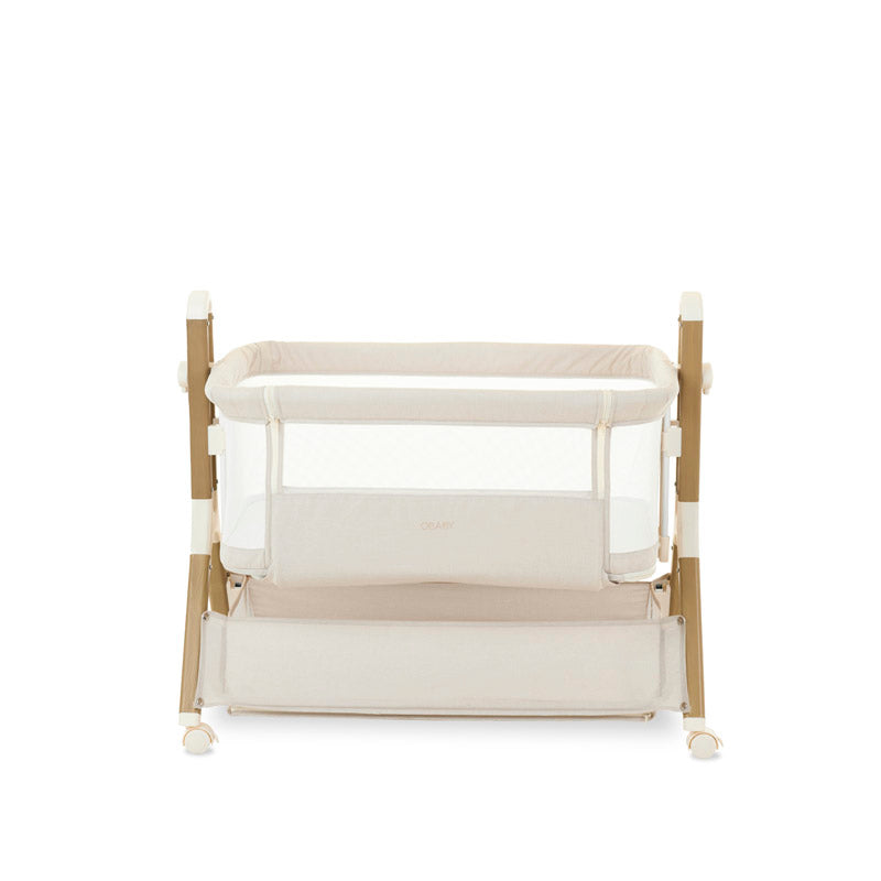 bedside crib on lower setting, oatmeal fabric with mesh sides, parent side has zipped panel that can be opened for easy access to the baby. wood effect frame & storage basket underneath. Caster wheels to move into position easily. 