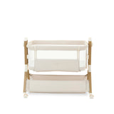 bedside crib on middle setting, oatmeal fabric with mesh sides, parent side has zipped panel that can be opened for easy access to the baby. wood effect frame & storage basket underneath. Caster wheels to move into position easily. 
