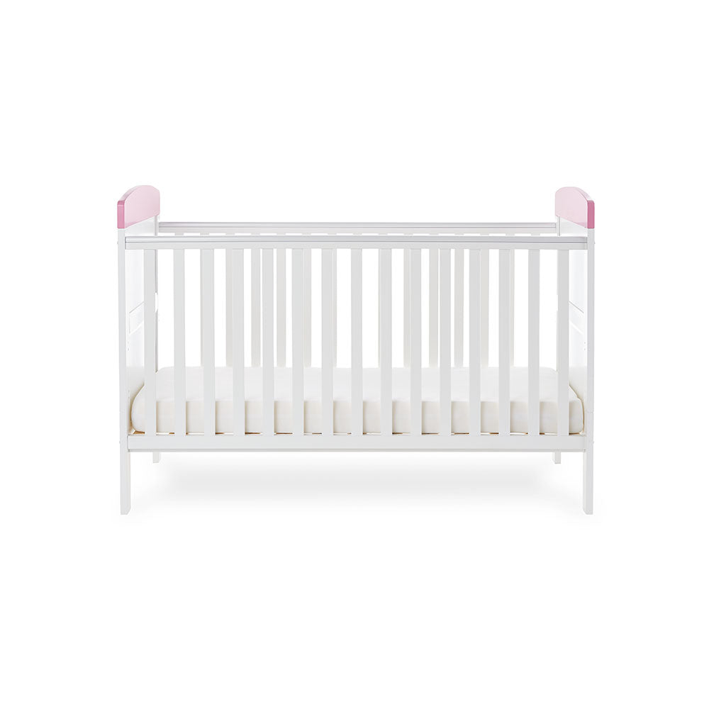 Cot Bed with base on lowest setting, solid ends with pink trim. 