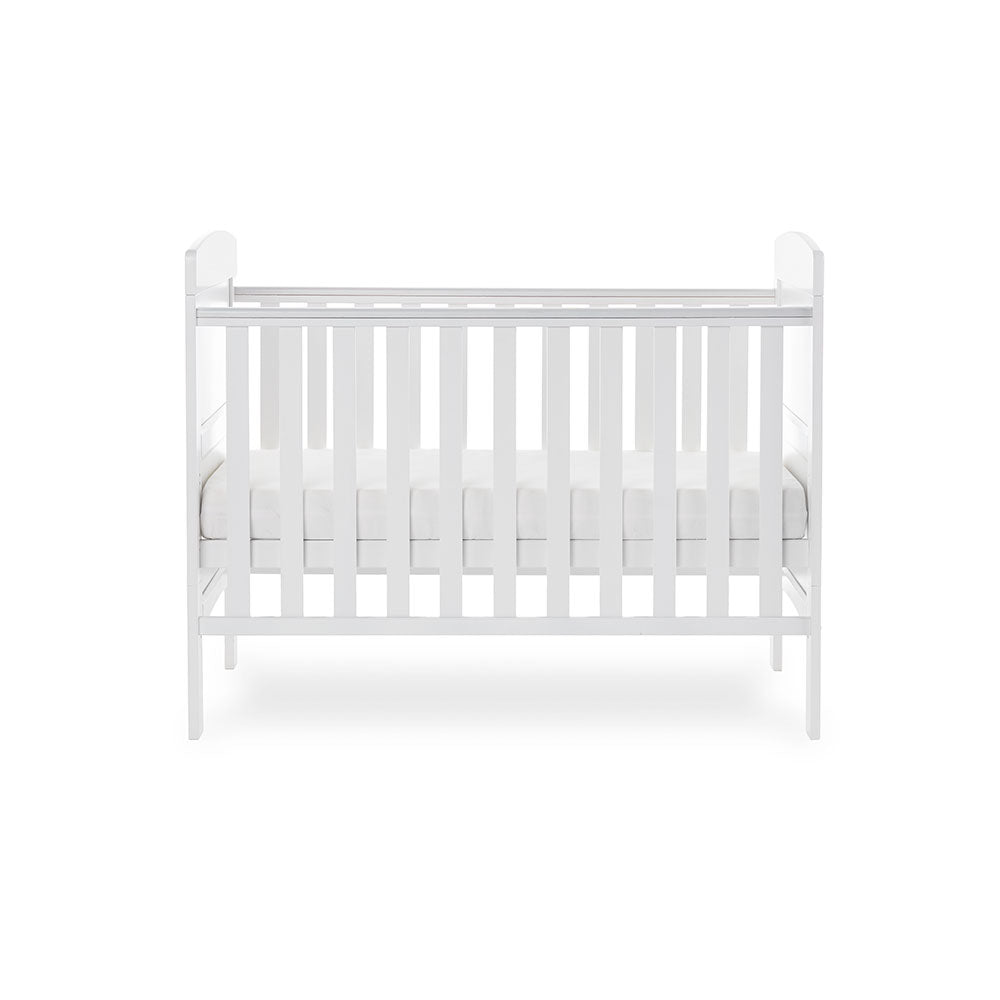 Side of mini cot bed, with teething rails on the sides, base on the middle setting. solid ebd with curved tops