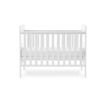 Side of mini cot bed, with teething rails on the sides, base on the middle setting. solid ebd with curved tops