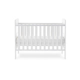 Side of mini cot bed, with teething rails on the sides, base on the middle setting. solid ebd with curved tops
