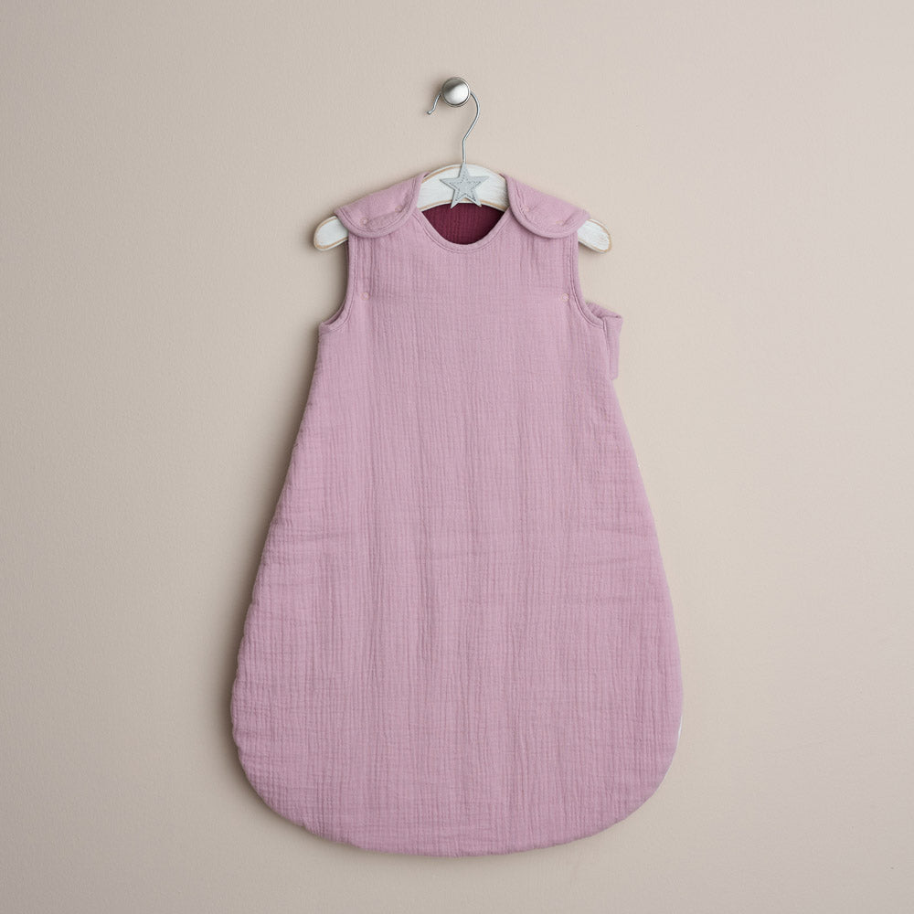 Pink baby sleeping bag on a hanger against a beige background