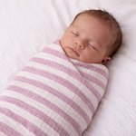 Newborn baby swaddled in a pink and white striped muslin blanket on a white background