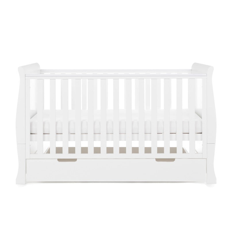 Sleigh cot bed with curved edges, solid  ends, teething rails fitted on the sides, base on the middle setting, under drawer included with cut out open handles. 