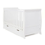 Sleigh Cot Bed with curved edges, solid ends, teething rails on the sides. Base on the lowest setting. Under drawer included with open cut out handles. 