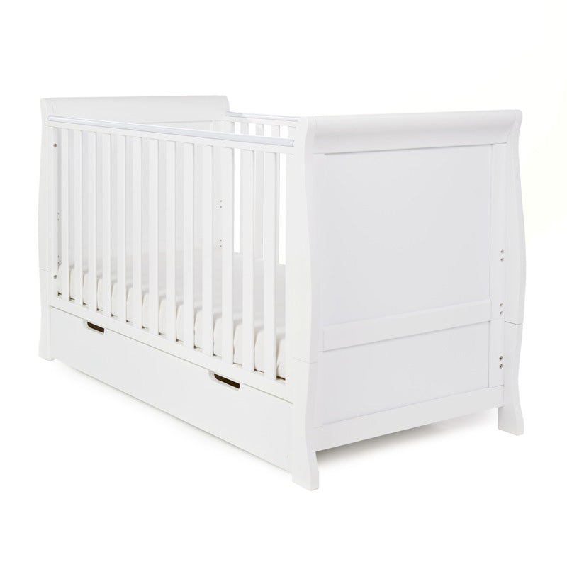 Sleigh Cot Bed with curved edges, solid ends, teething rails on the sides. Base on the lowest setting. Under drawer included with open cut out handles. 
