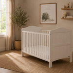 white cot  bed, with curved foot & head end. Teething rail on the rails. 