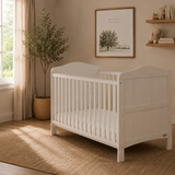 white cot  bed, with curved foot & head end. Teething rail on the rails. 